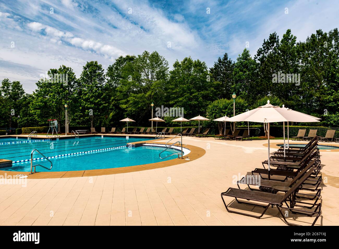 Swimming pool deck lounge chairs lined up by the side of a pool Stock