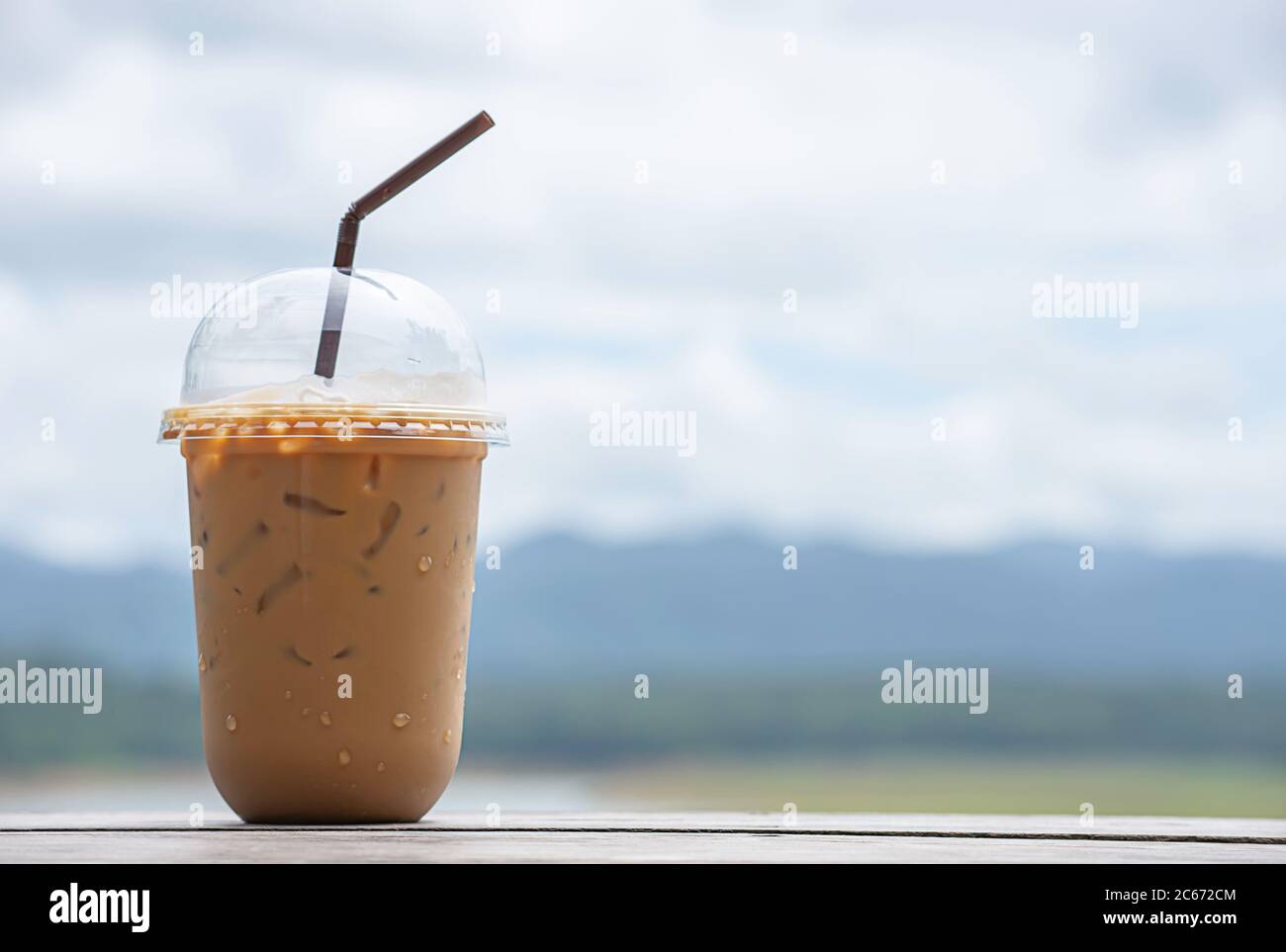 https://c8.alamy.com/comp/2C672CM/glass-of-cold-espresso-coffee-on-the-table-background-blurry-views-sky-water-and-mountain-2C672CM.jpg