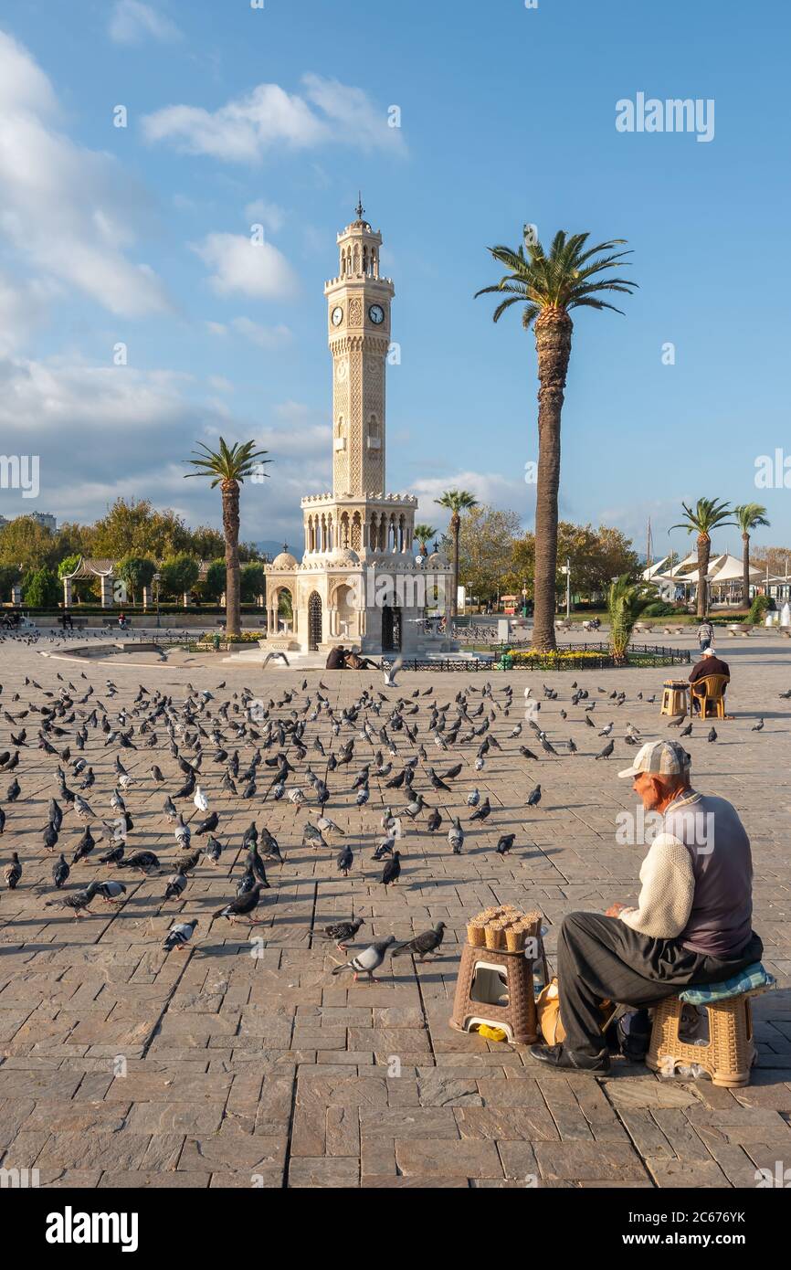 Unidentified turkish senior man selling food for pigeons near the Clock Tower of Izmir at Konak Square in Turkey Stock Photo