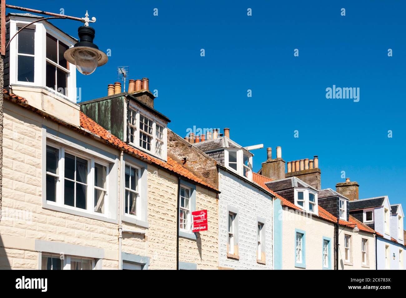 A terrace row of cottages on the seafront at Mid Shore Pittenweem in East Neuk of Fife, one with a For Sale sign. Stock Photo