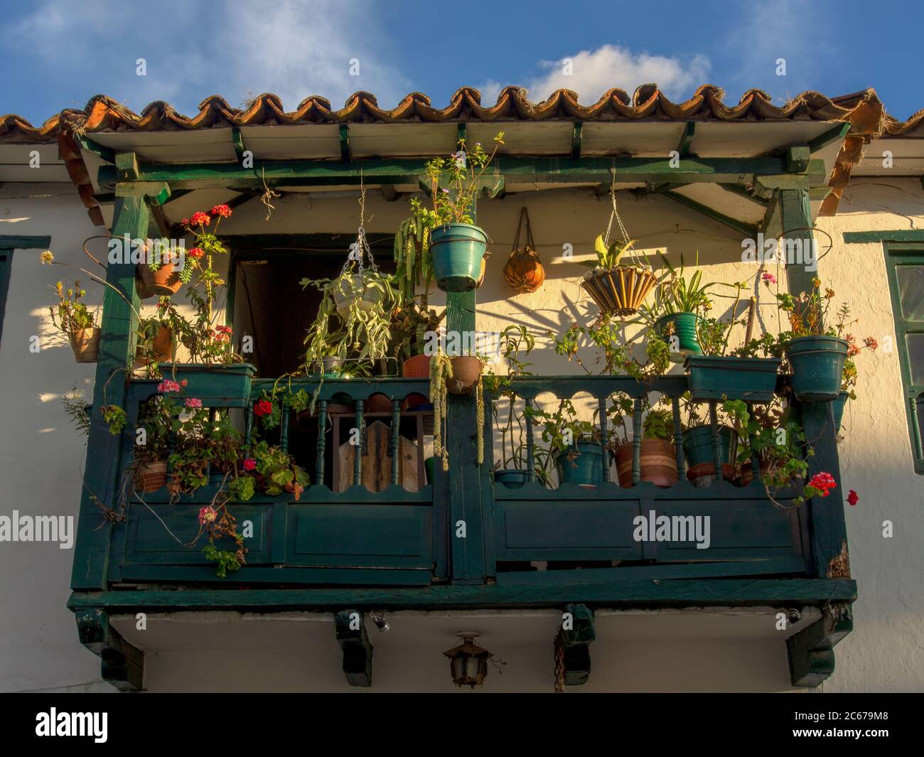 A wooden balcony decorated with pot plants at sunset, captured in the colonial town of Villa de Leyva, in the Ricaurte Province, part of the Boyacá De Stock Photo