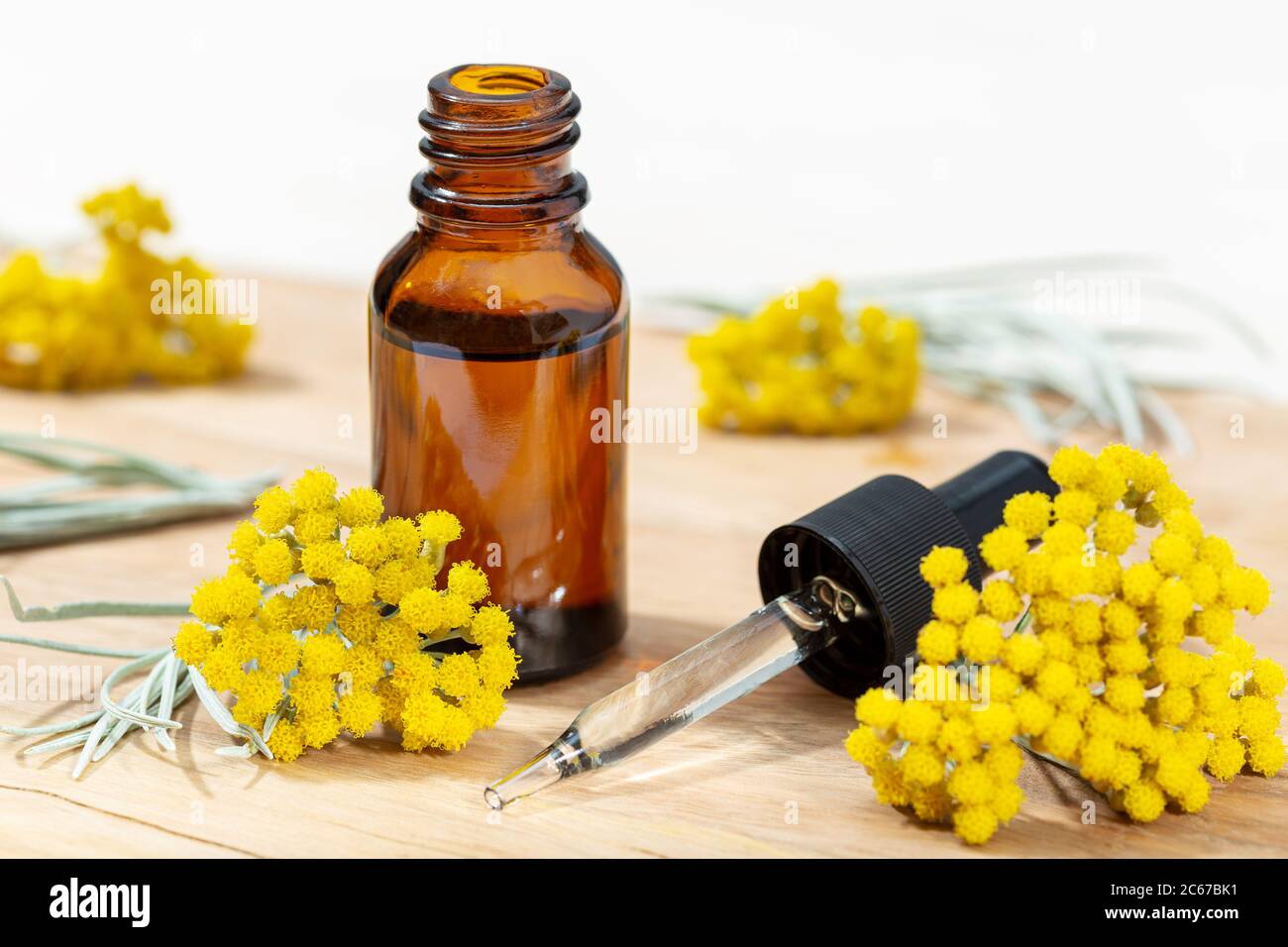 Helichrysum essential oil in amber bottle and pipette. Herbal remedies oil Stock Photo