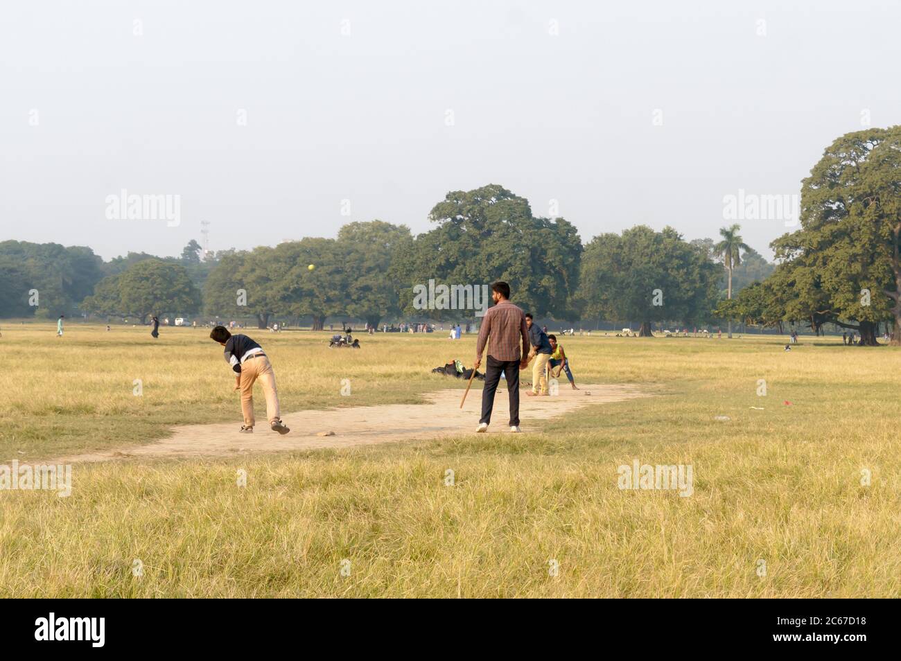 Local Indian boys having fun playing cricket game in Maidan area in the winter sunset evening time near Eden Gardens stadium, city of joy, Kolkata, We Stock Photo