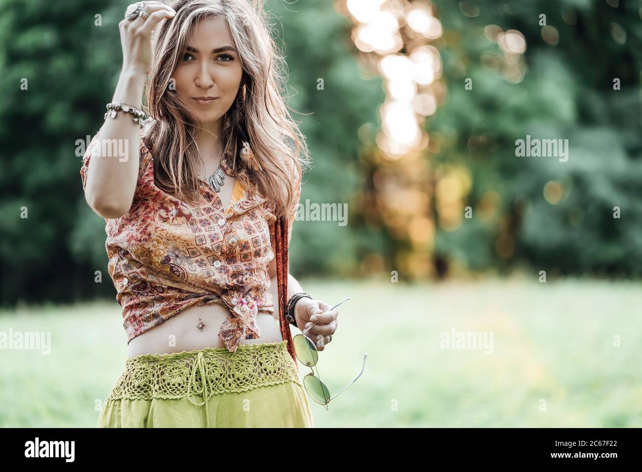 Portrait of Beautiful young woman wearing bohostyle clothes posing in the rays of the evening sun, sunset. Boho style fashion, female wearing silver Stock Photo