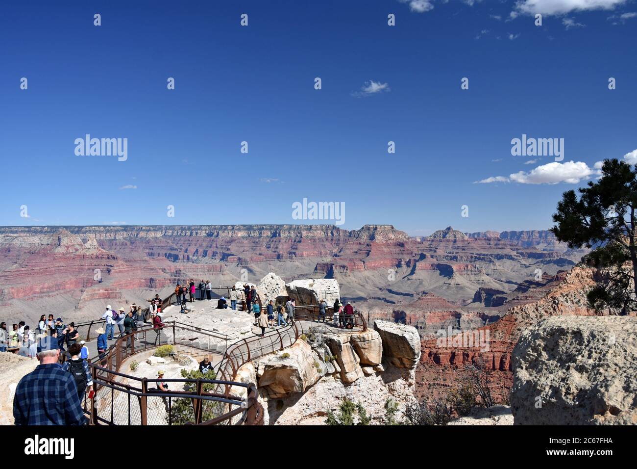 Mather Point on the south rim of the Grand Canyon.  Visitors are seen enjoying the views, posing and taking photos of the canyon around them. Stock Photo