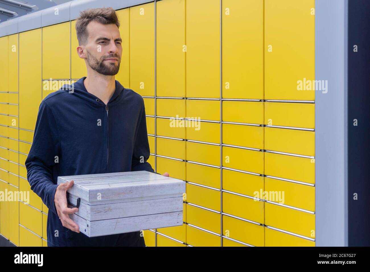 Man holding parcel and sending using yellow self-service post terminal ...