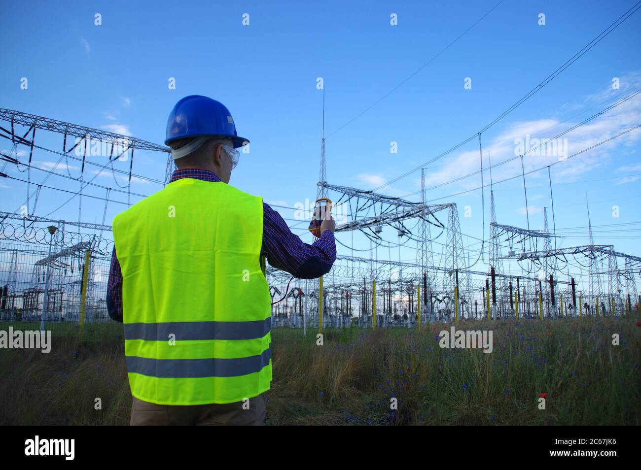 Engineer in a helmet with a meter. Electric power production and energy industry. Stock Photo