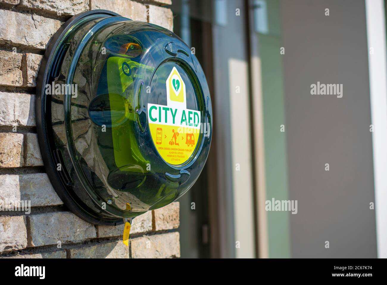 Green automated external defibrillator CITY AED on the street in the city. AED CPR rescue kit box. Medical device to deliver an electrical shock Stock Photo