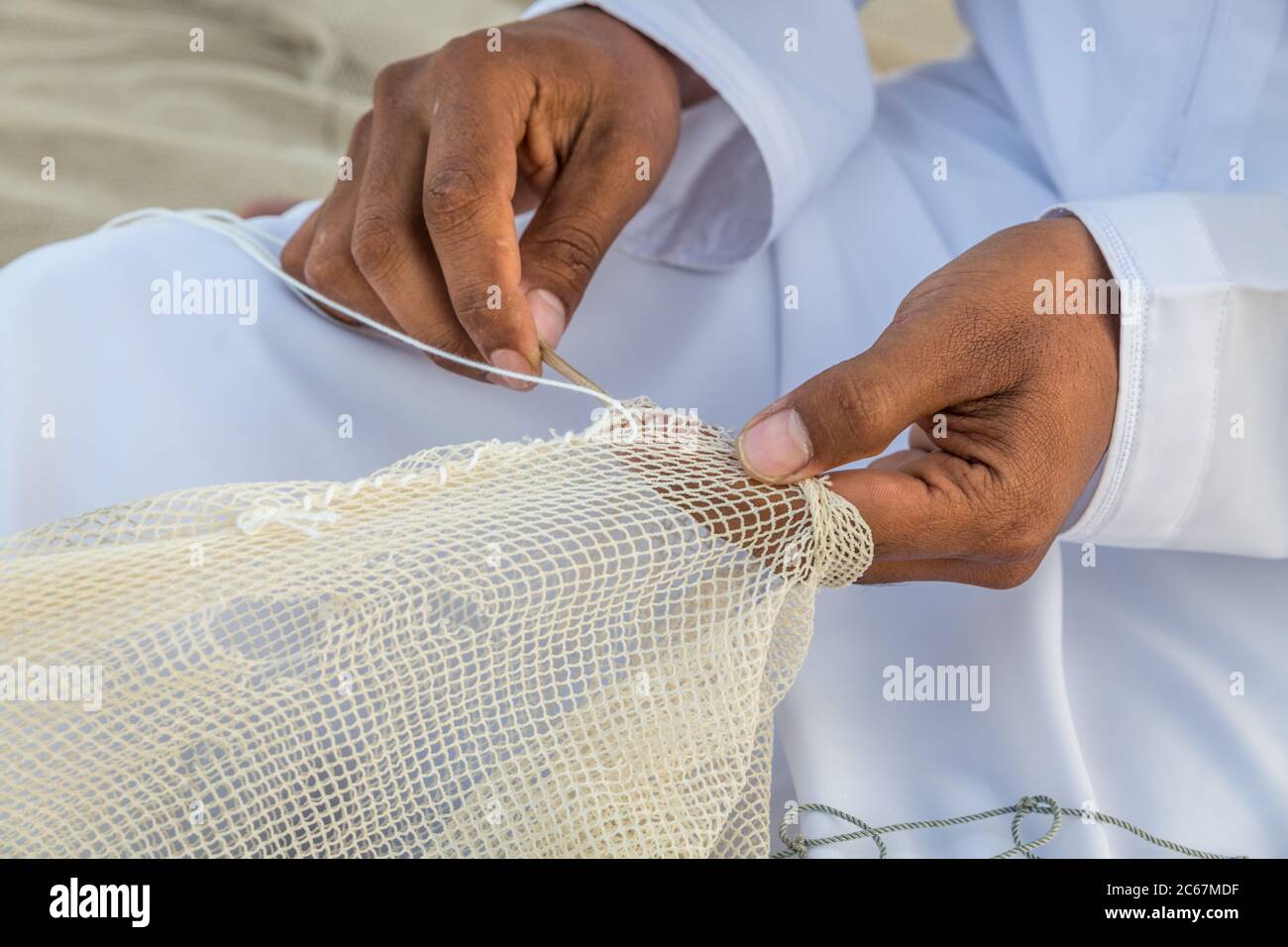 Close up image of the hands of Arabic man weaving fishnet 'fishing net' Stock Photo