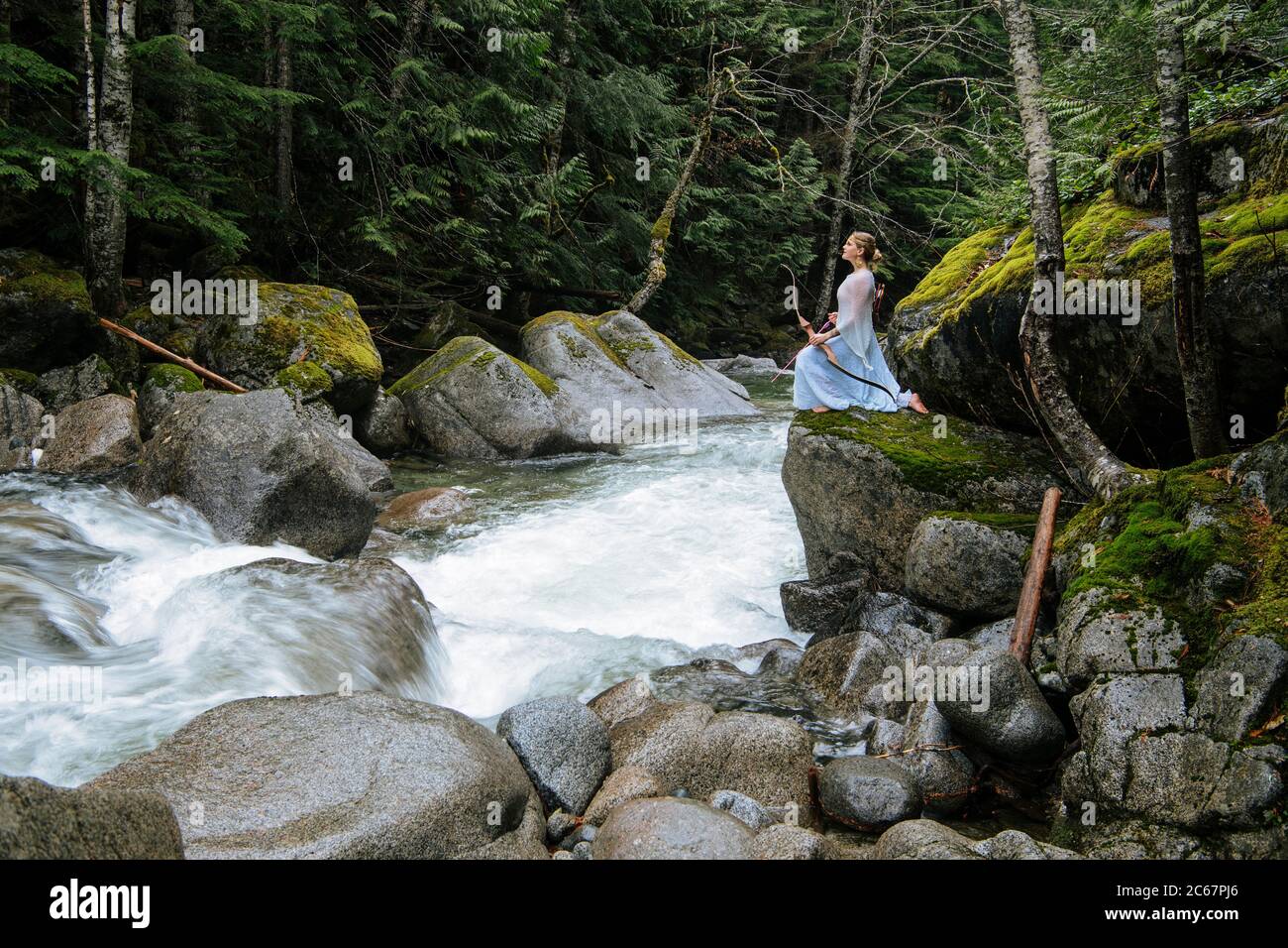 Woman with bow amidst scenic forest, Deception Falls National Recreation Area, Washington, USA Stock Photo