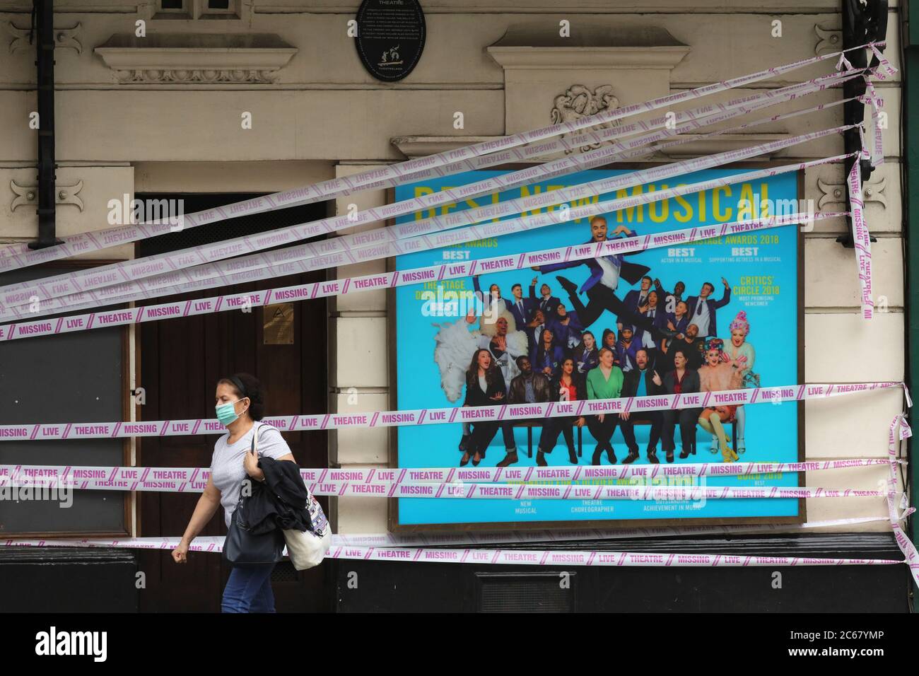 London, Britain. 7th July, 2020. A woman walks past the Apollo Theater wrapped with pink tapes in London, Britain, on July 7, 2020. Britain's arts, culture and heritage industries will receive a 1.57-billion-pound (1.96-billion-U.S. dollar) rescue package to help weather the impact of the coronavirus pandemic, the government has announced. Credit: Tim Ireland/Xinhua/Alamy Live News Stock Photo