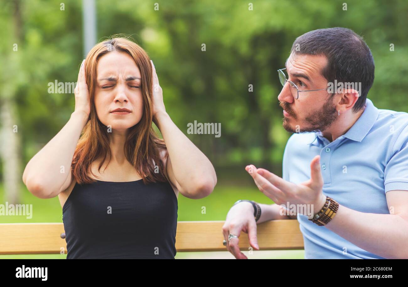 An arguing couple view, man is dictating, woman close ears and unconcerned, doesn't want to hear Stock Photo