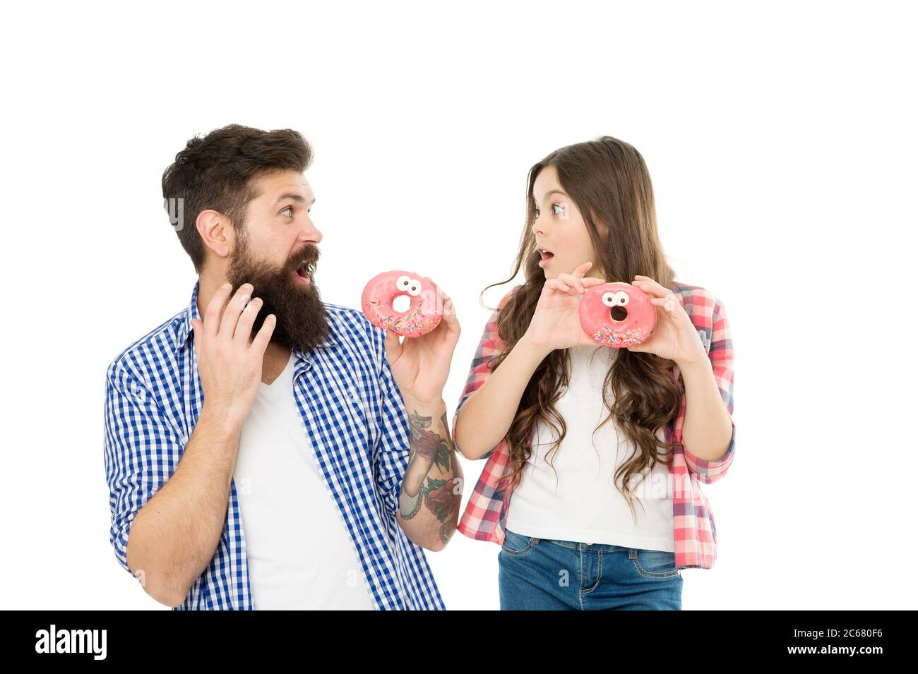 Sweets and treats concept. Daughter and father eat sweet donuts. Bakery shop. Fathers day. Sweet tooth. Girl child and dad hold glazed donuts. Cheerful family. Happiness and joy. Hungry kid. Stock Photo