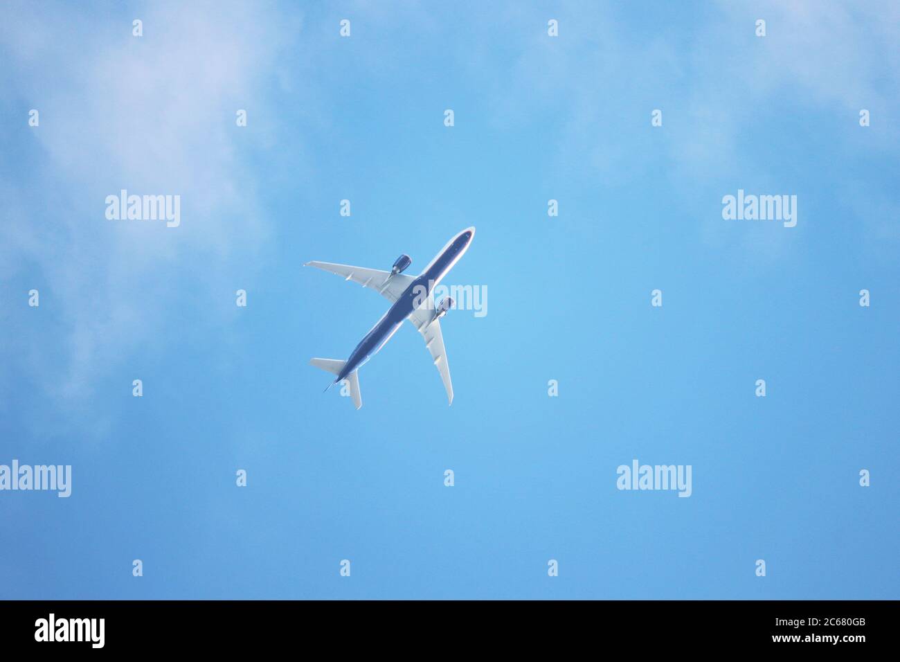 Airplane flying in the blue sky with white clouds, bottom view. Two-engine commercial plane after taking off Stock Photo