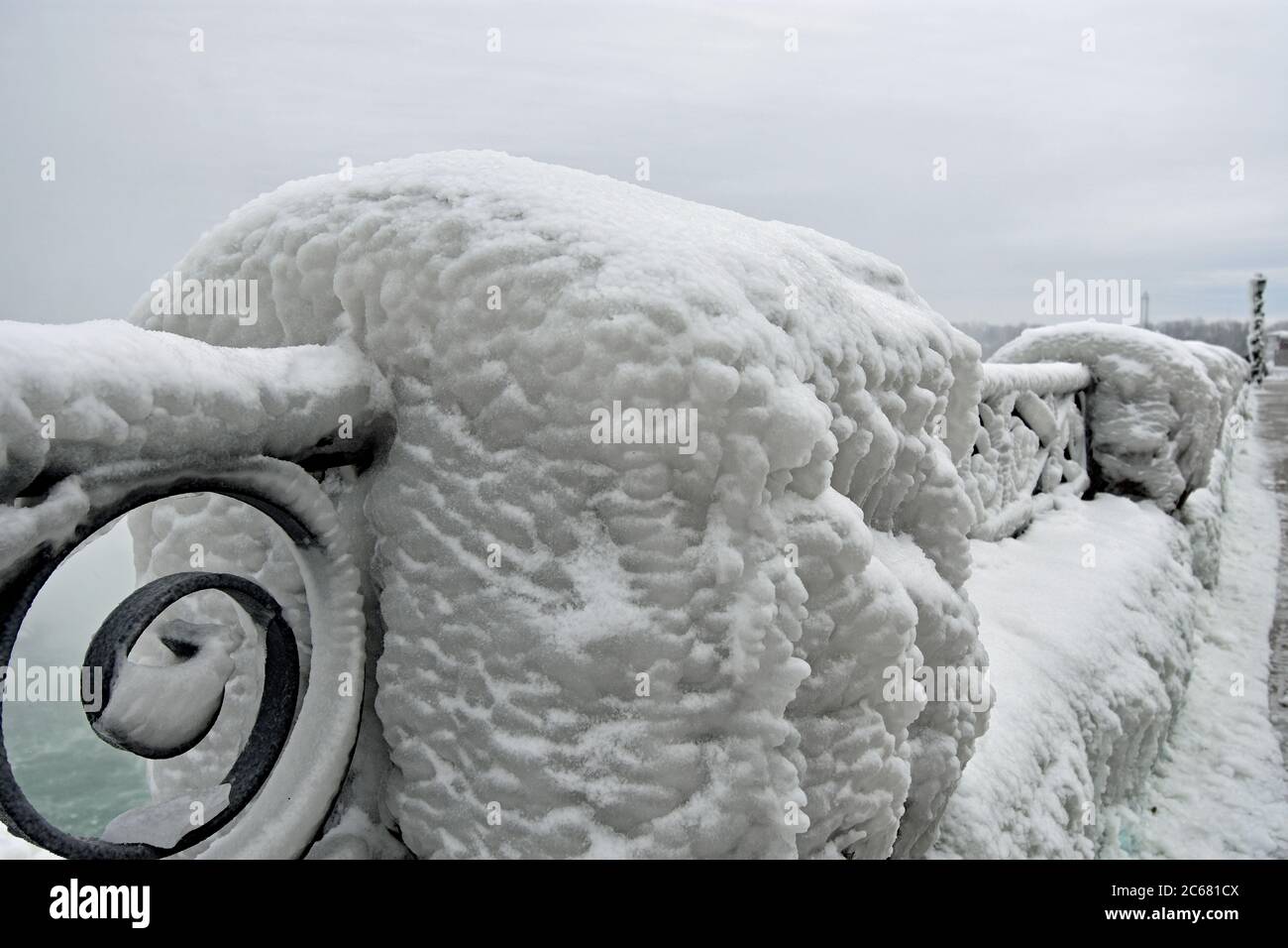 Ornate railings along the edge of Niagara falls covered in thick white ice due to the mist from the falls. Stock Photo