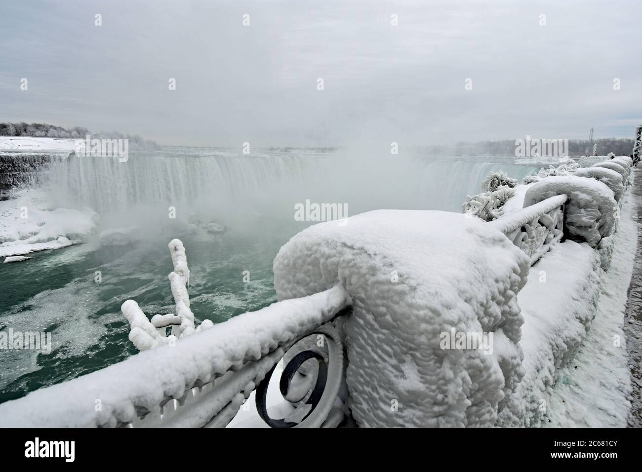 Ornate railings along the edge of Niagara falls covered in thick white ...