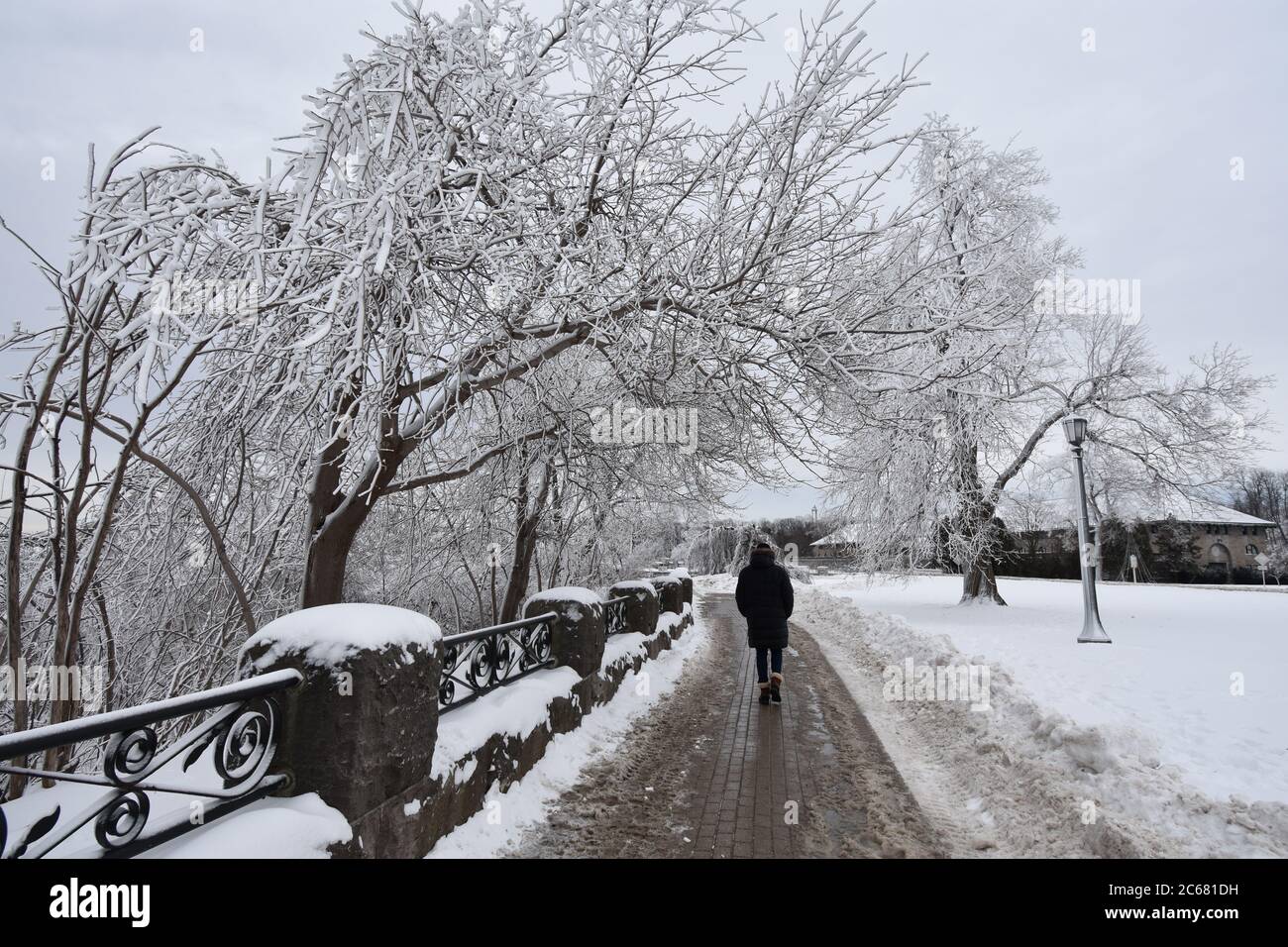 The riverside path in Queen Victoria Park during wintertime at Niagara Falls on the Canadian side. A man is enjoying the walk and view in a warm coat. Stock Photo