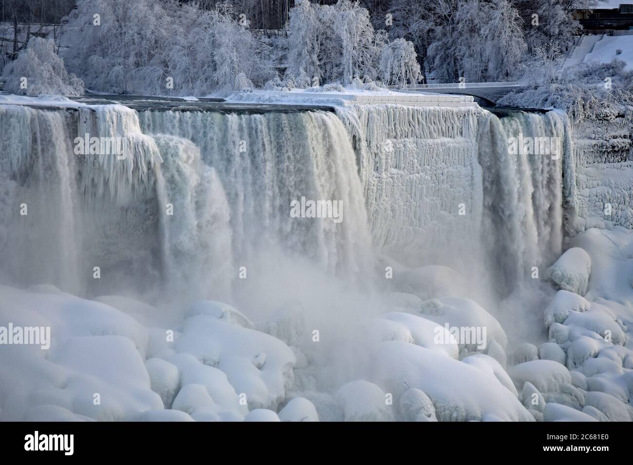 American Falls and Bridal Veil falls during winter.  Frozen Trees and boulders and snow on the ground. Mist rising from the falls. Niagara Falls. Stock Photo
