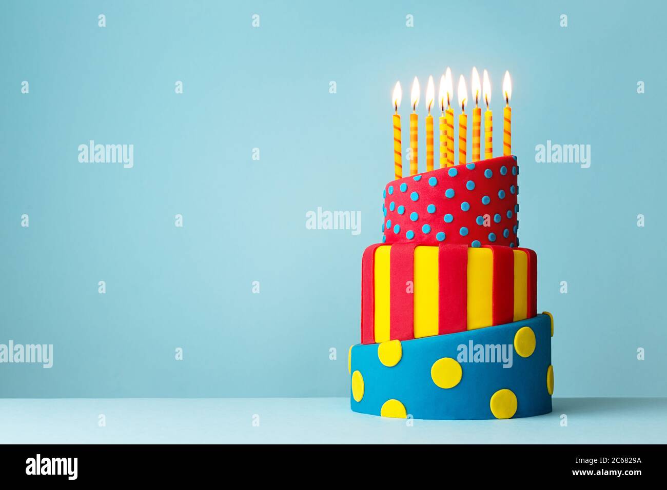 Colorful topsy turvy birthday cake with candles Stock Photo