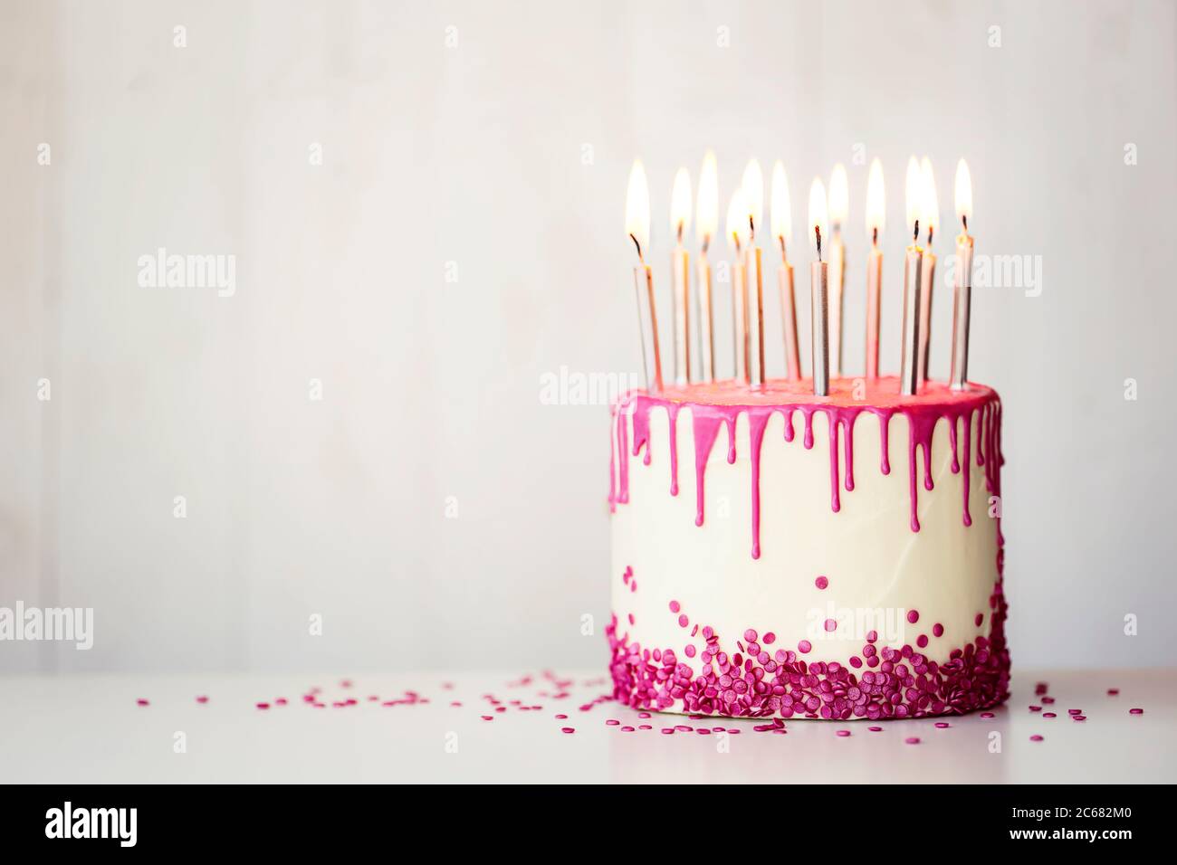 Birthday cake with pink drip icing and birthday candles with copy space to side Stock Photo Alamy