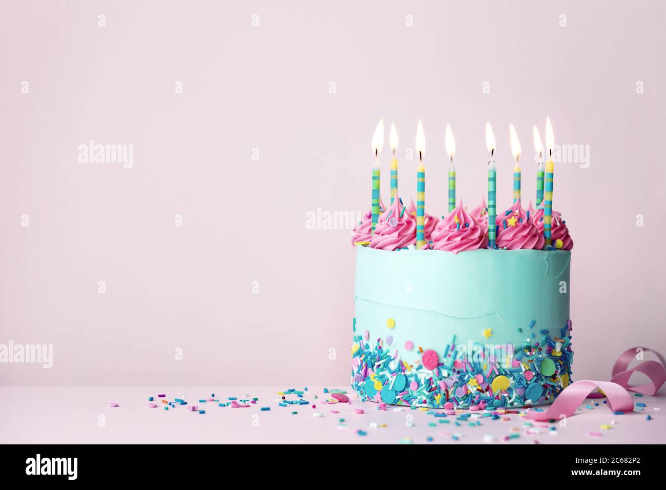 Pastel colored birthday cake with sprinkles and pink buttercream swirls Stock Photo