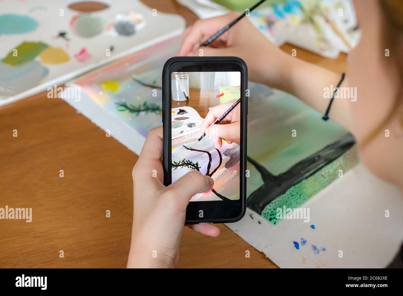 Female hand holding a smart phone taking photos - video of herself drawing a paint.  Stock Photo