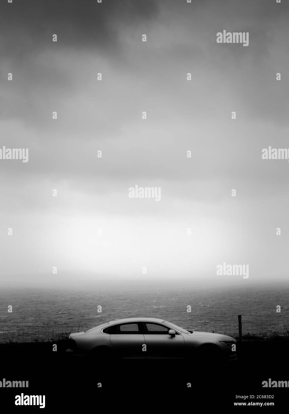 Silver car parked at Atlantic coastline under dramatic sky, County Kerry, Ireland Stock Photo