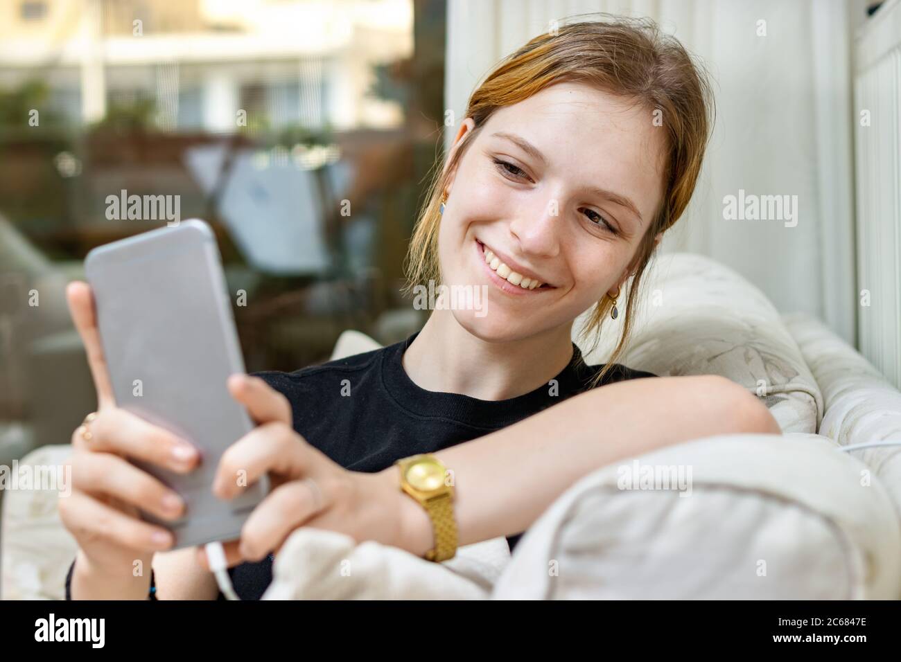 Teenage girl taking a selfie with a smart phone smiling sitting at home Stock Photo