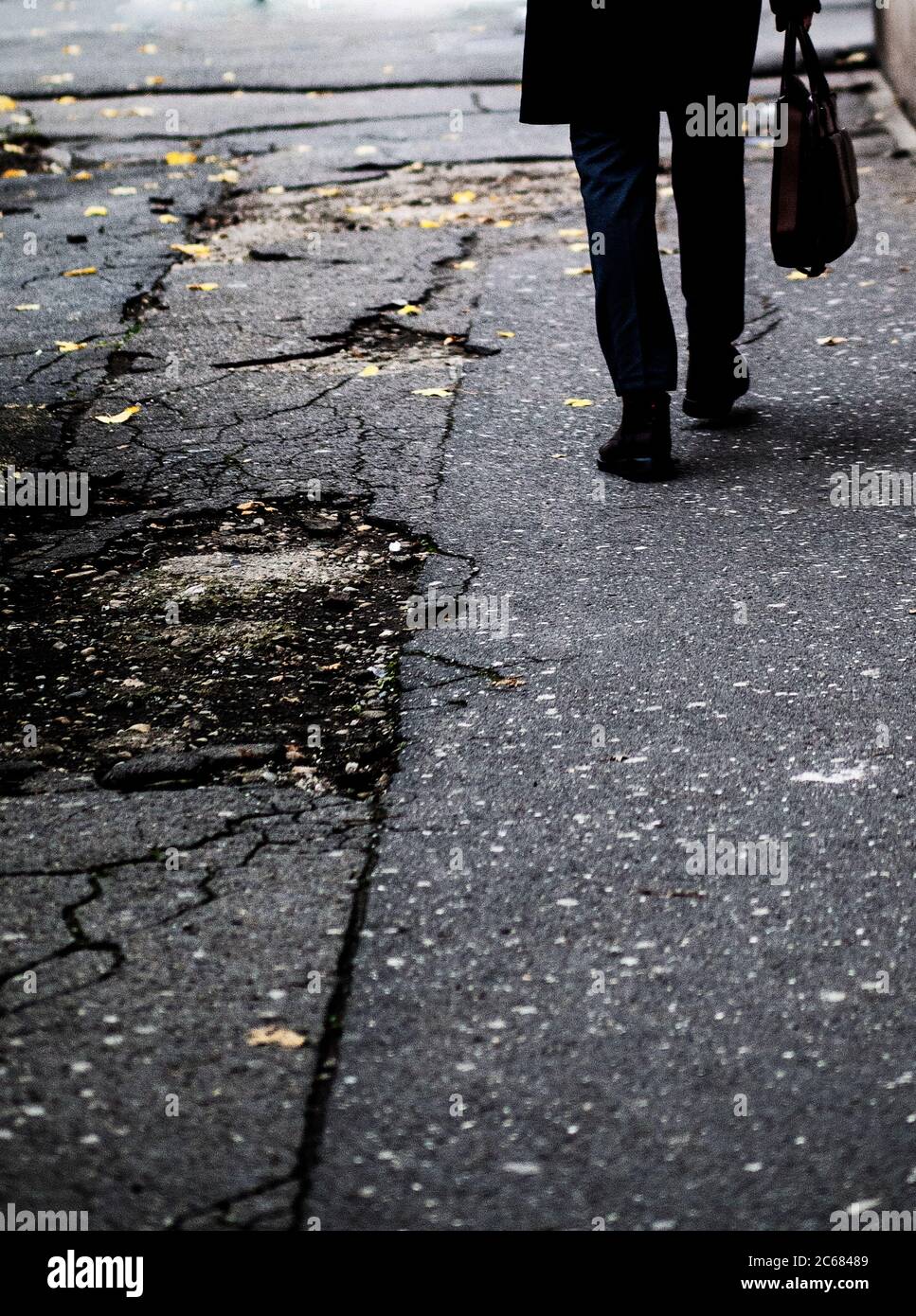 Man walking on sidewalk carrying a bag Stock Photo