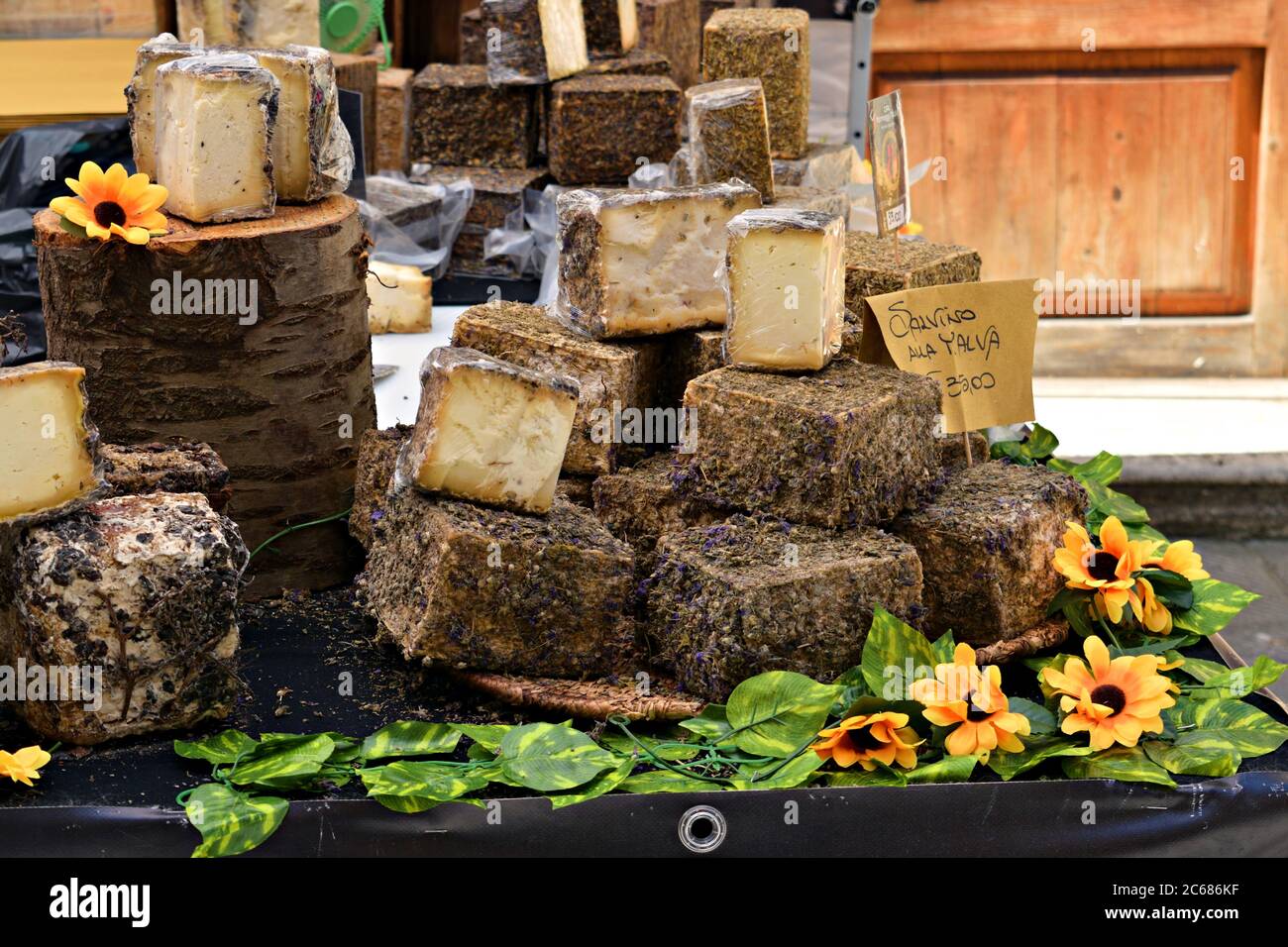 close up of various typical Italian cheeses for sale on a food counter in the streets of the medieval village of Asciano in Tuscany, Italy Stock Photo