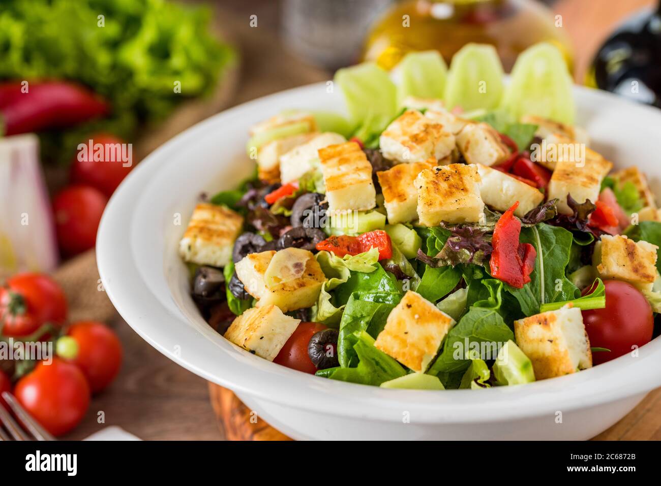 Healthy mixed salad in white bowl on wooden table. Stock Photo