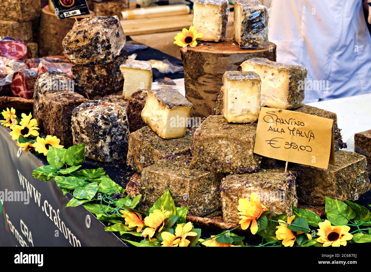 close up of various typical Italian cheeses for sale on a food counter in the streets of the medieval village of Asciano in Tuscany, Italy Stock Photo