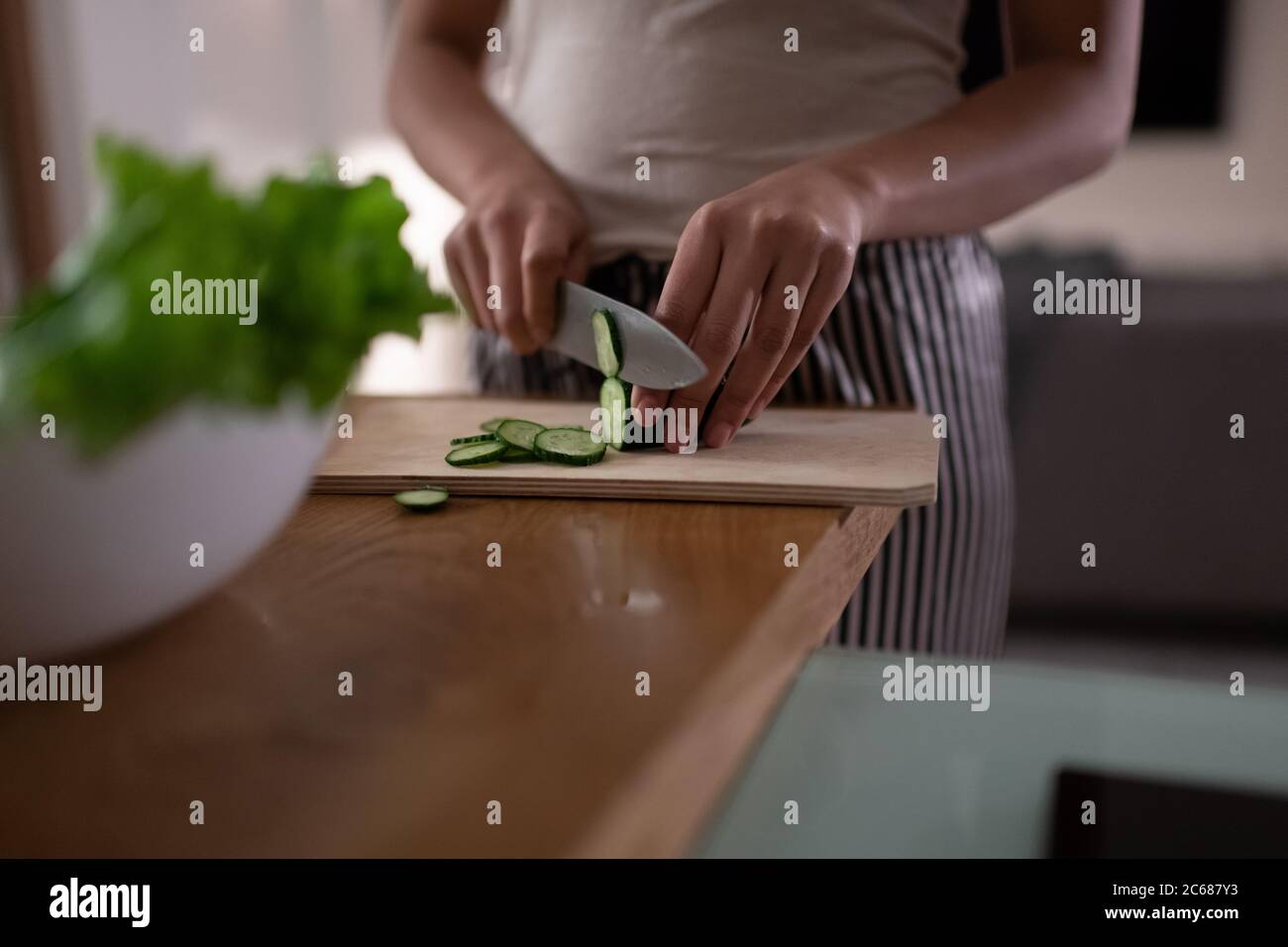 Cropped black lady chopping cucumber while cooking healthy dish for dinner at home Stock Photo