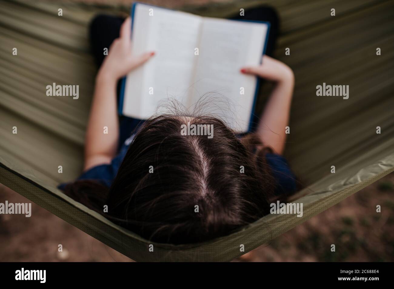 Center overhead frame of teen girl reading in hammock Stock Photo