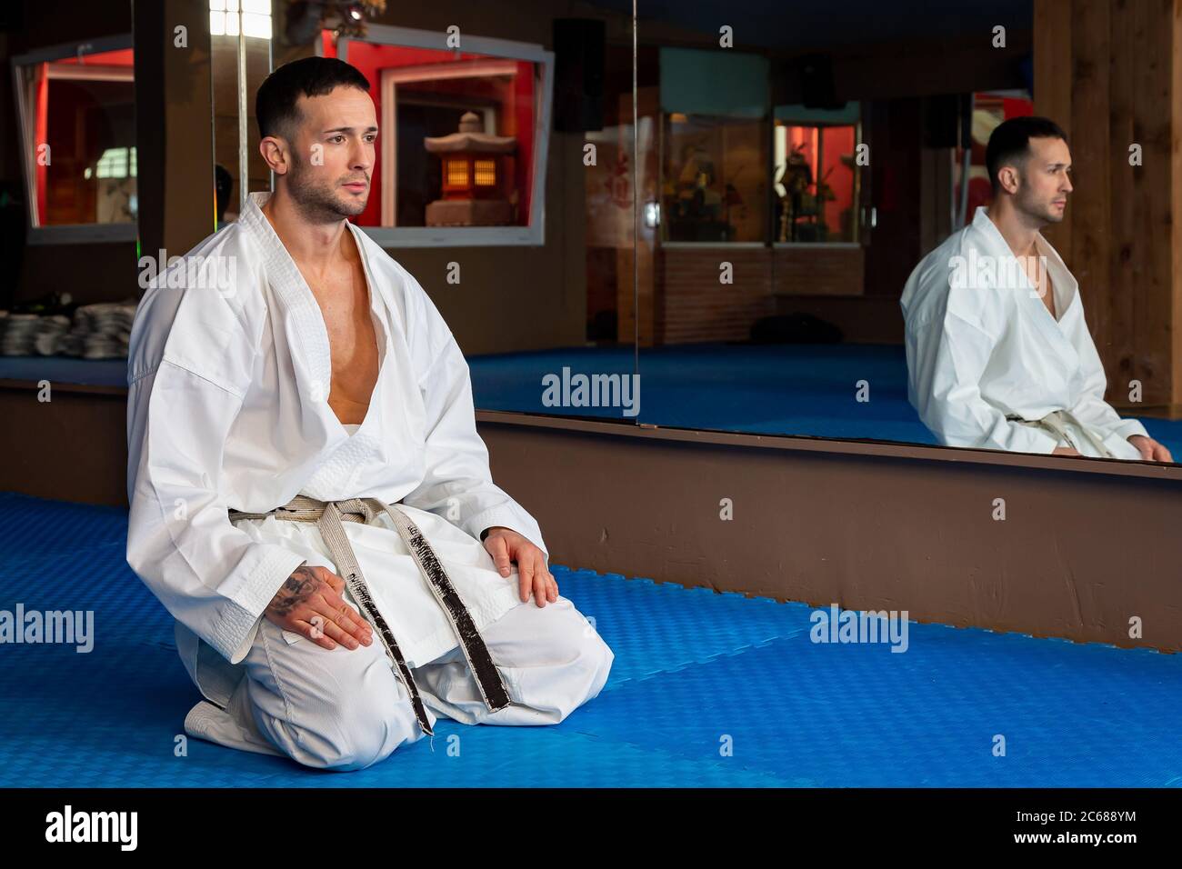 Karate man with traditional Japanese sitting posture on tatami. He is wearing white kimono Stock
