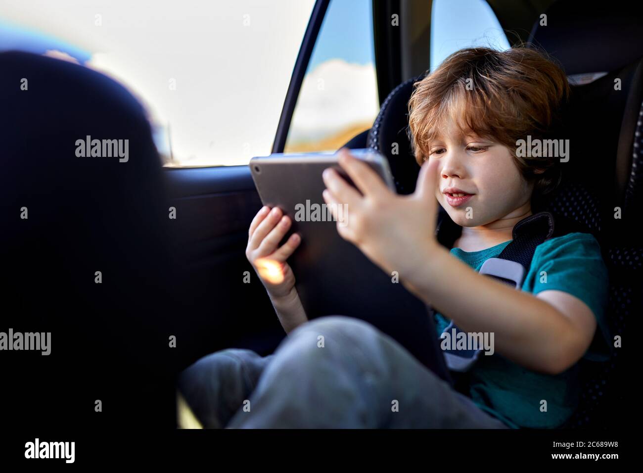 Cute boy using digital tablet while traveling in car during weekend Stock Photo