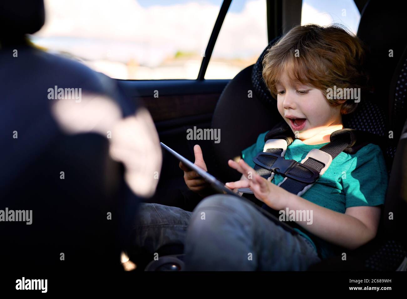 Cute boy using digital tablet while sitting in car Stock Photo