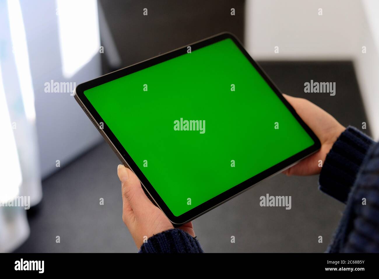 over shoulder of people holding green screen tablet computer. Blur background Stock Photo
