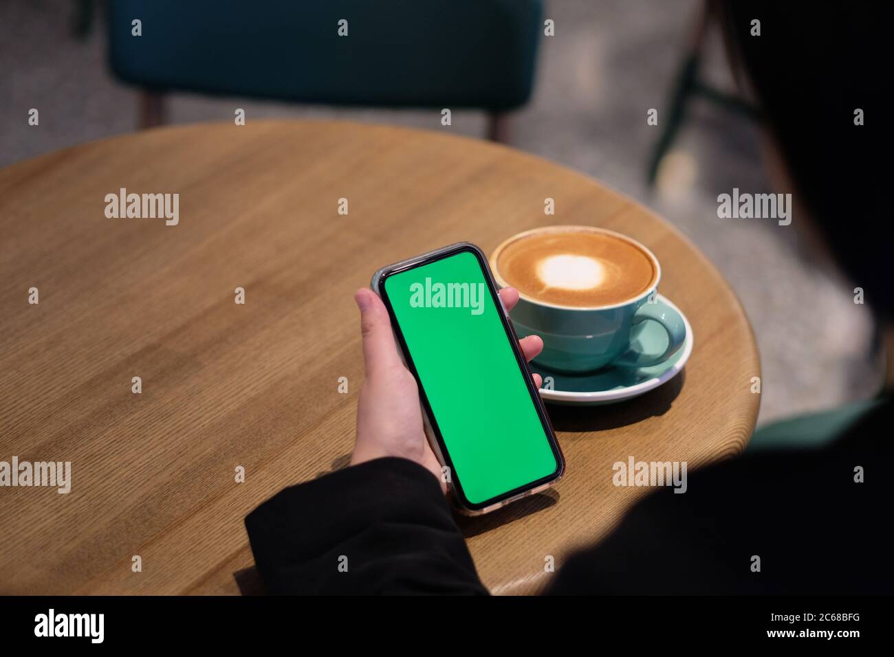 over should of people holding green screen smartphone in cafe. blur background Stock Photo