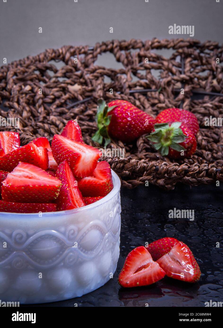 Whole strawberries and some strawberry slices next to each other from a close angle of view. Stock Photo