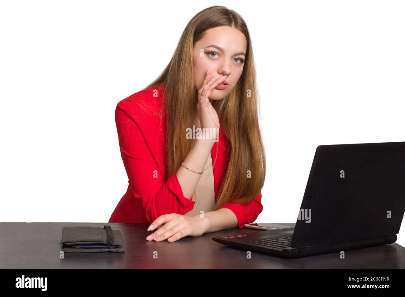 A young business office woman in a red suit a background isolated in white, sitting at the table with his head propped up in front of his laptop Stock Photo