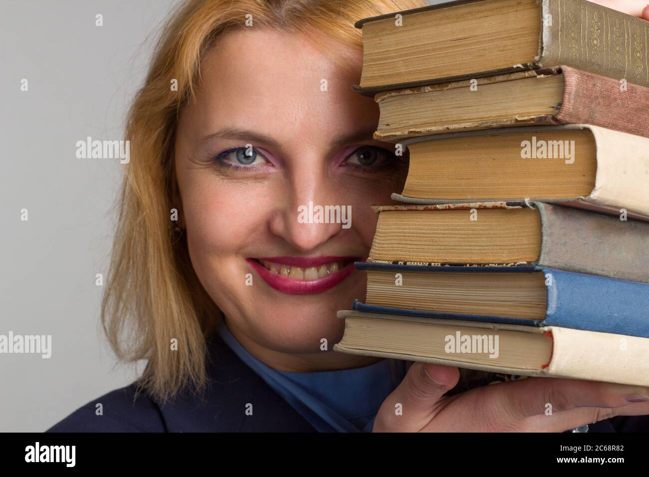 plus size caucasian business office woman. isolated in white. looks out from behind a stack of books. The concept of adult learning Stock Photo