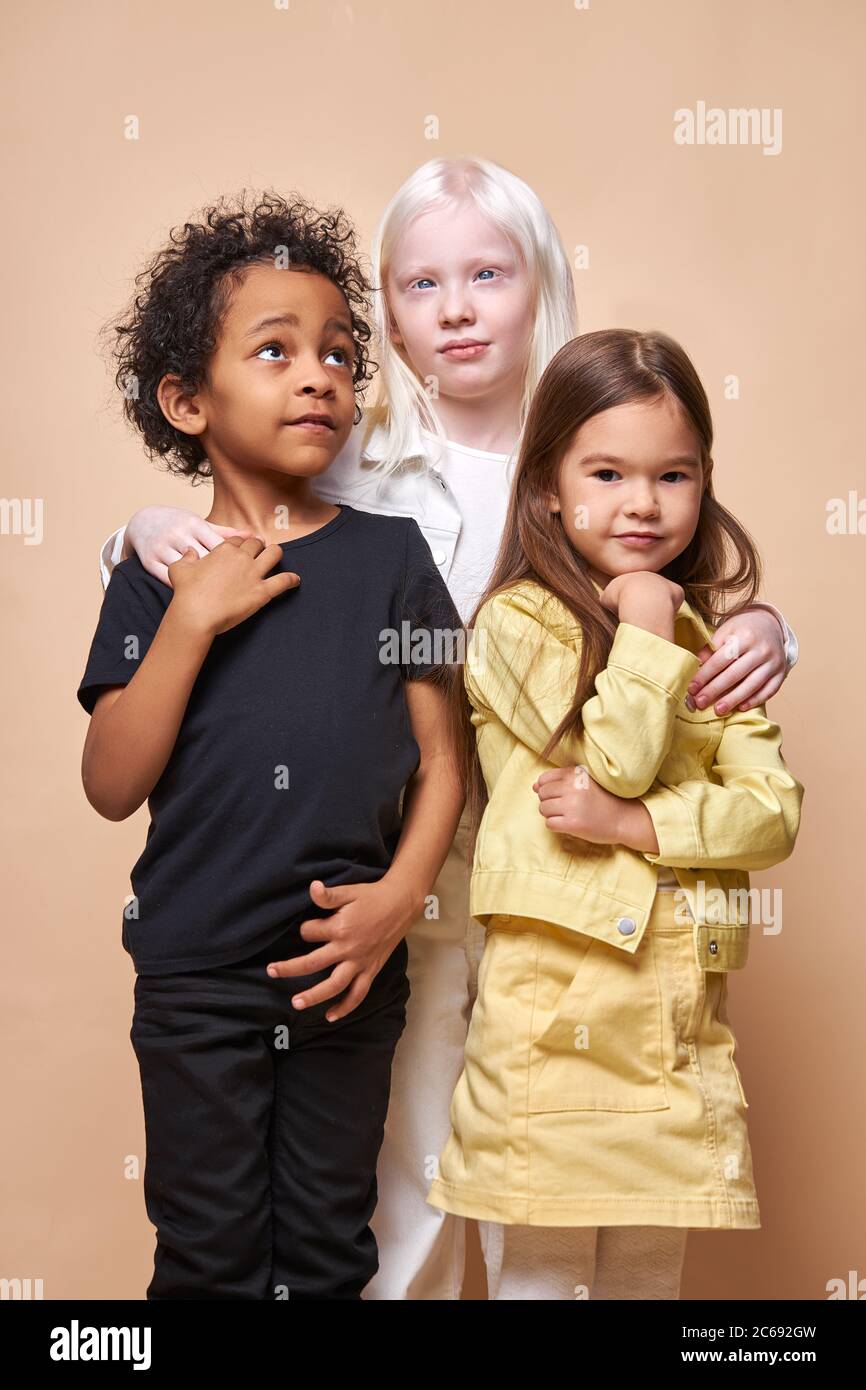 portrait of adorable diverse children isolated. black african, albino and european children stand together, close friendship between them. people dive Stock Photo