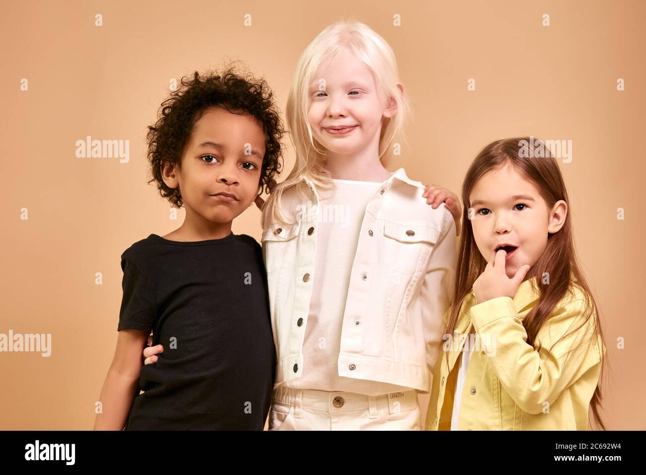 portrait of adorable diverse children isolated. african, albino and european children stand together, close friendship between them. people diversity, Stock Photo