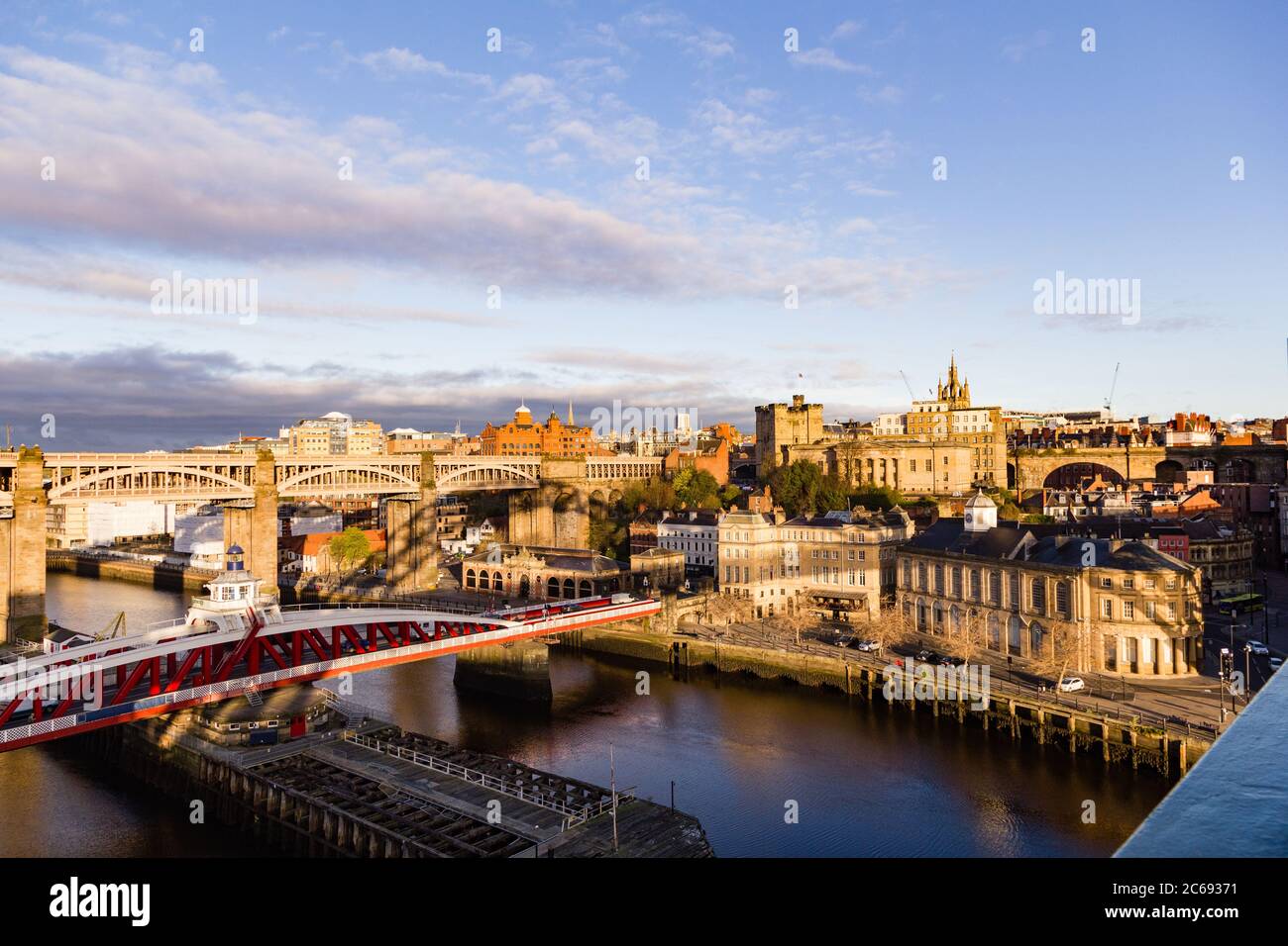 Newcastle Upon Tyne Quayside and Grainger Town areas coloured golden at sunrise, with shadow of the iconic Tyne Bridge cast across the buildings Stock Photo