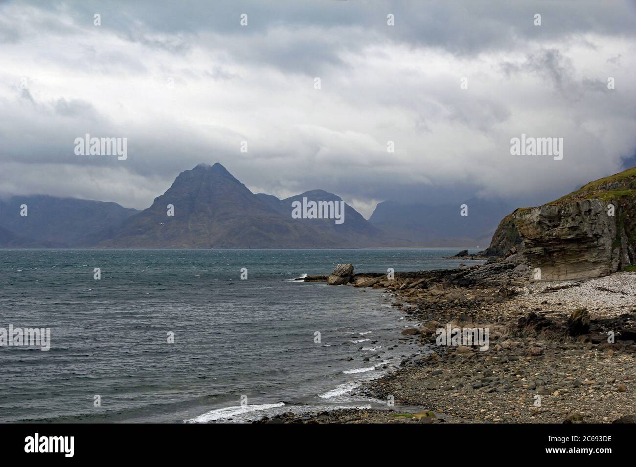 Dark Cuillins rise from the sea on an overcast spring day on the Isle of Skye. Scotland Stock Photo