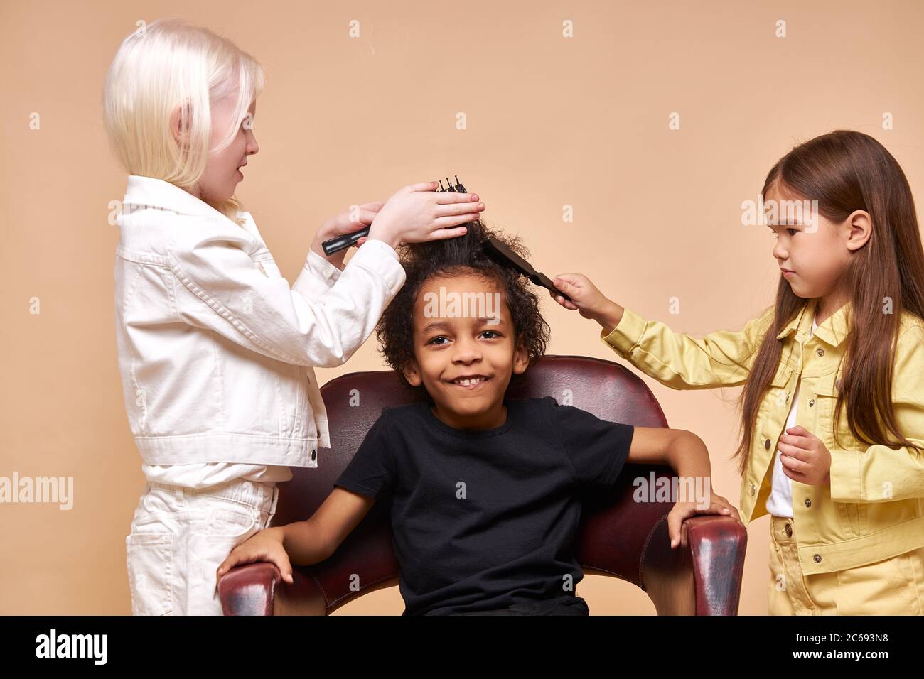portrait of friendly diverse kids playing hairdressers. two girls comb