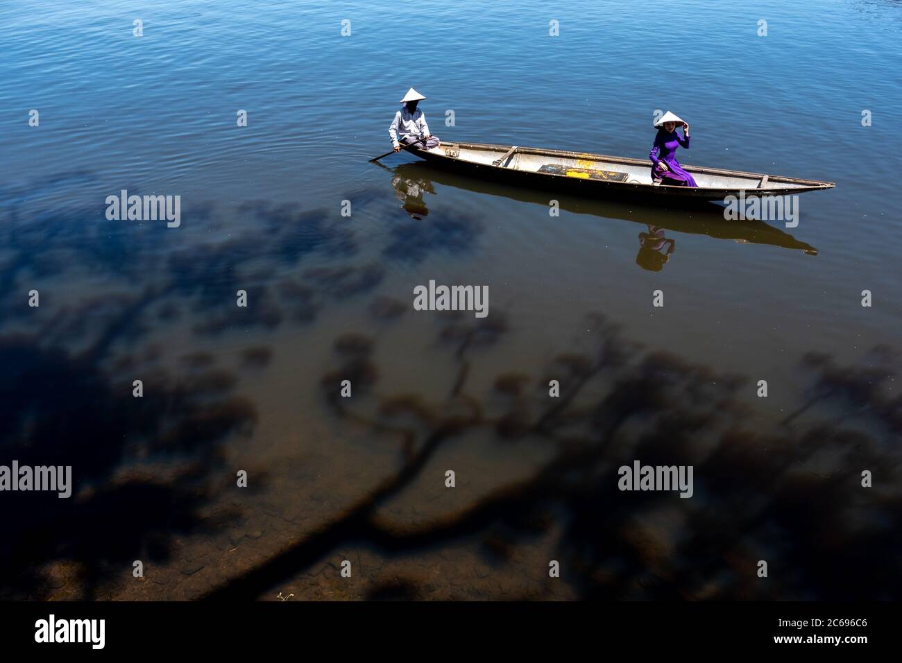 Two women in traditional clothing sitting in a boat, Vietnam Stock Photo