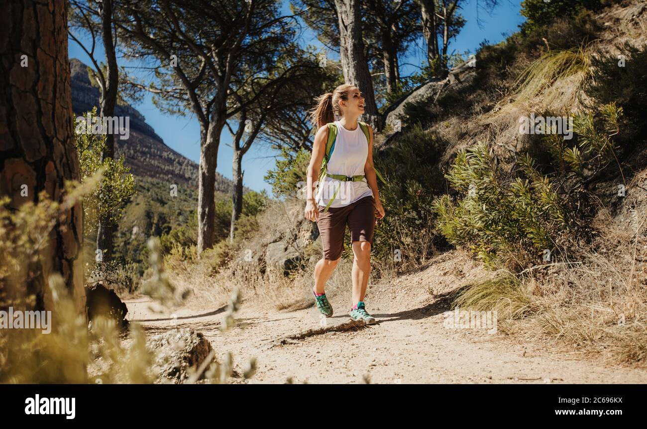 Woman walking on a mountain trail. Female on hiking trip looking up at the mountain. Stock Photo