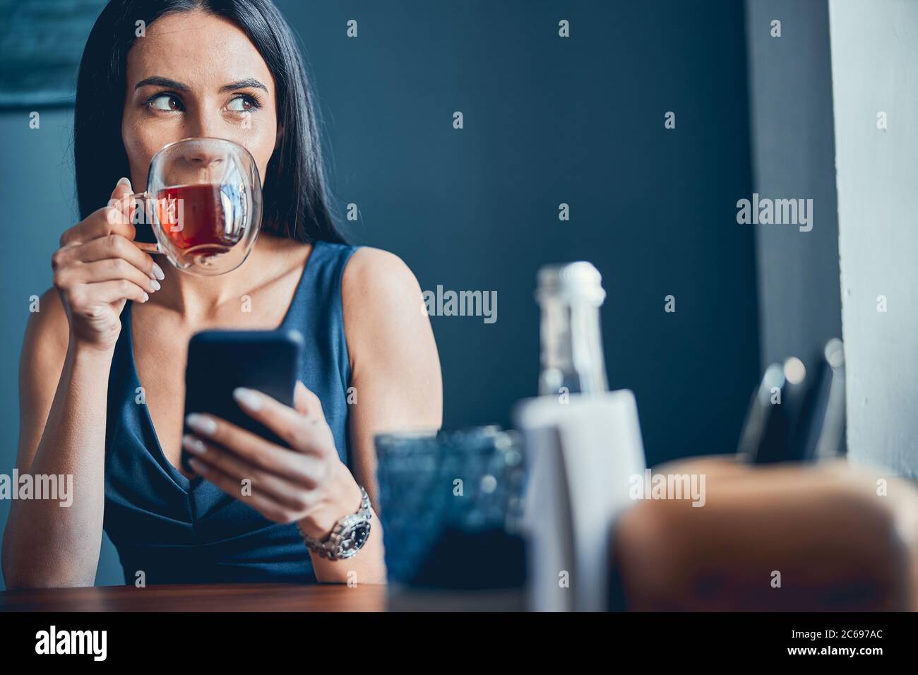 Businesswoman drinking tea and texting on mobile phone Stock Photo